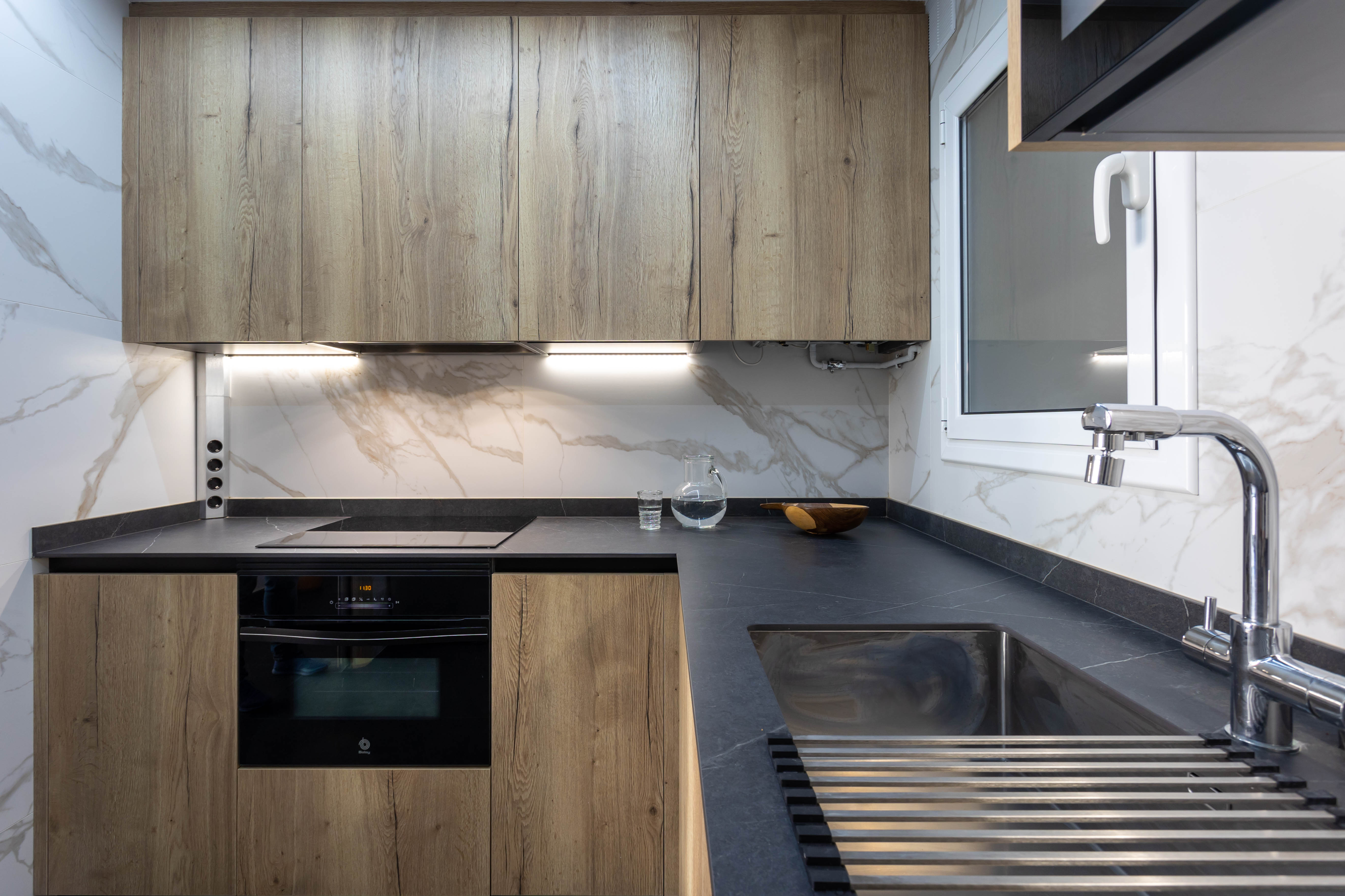 Cocina con mueble de madera y encimera de piedra oscura